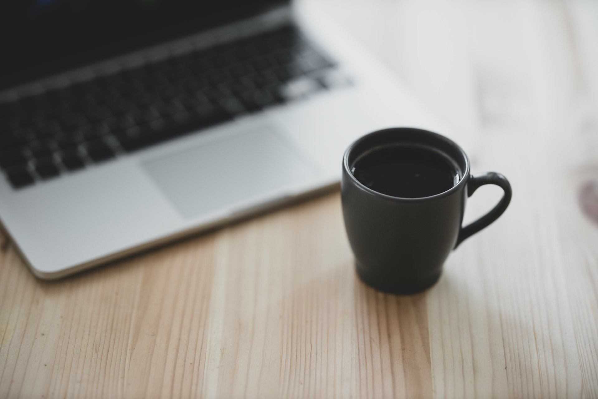 black ceramic mug beside macbook pro